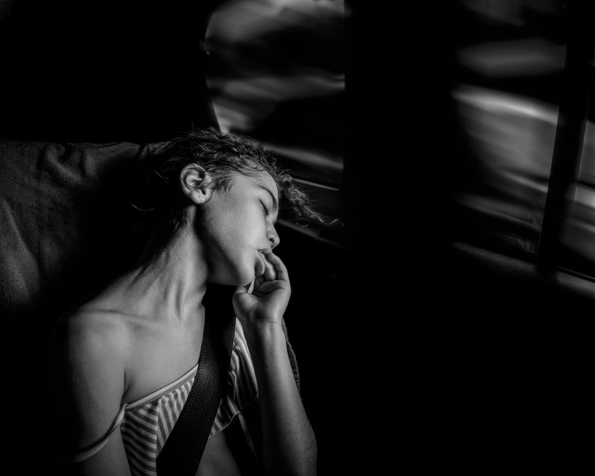 Black and white portrait of a woman sleeping in a car